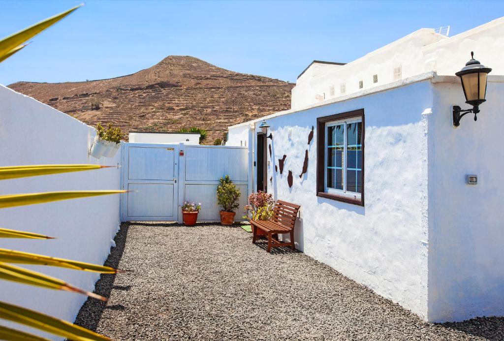 MáguezEco Casa Atalaya的白色的房子,有长凳,有山地背景