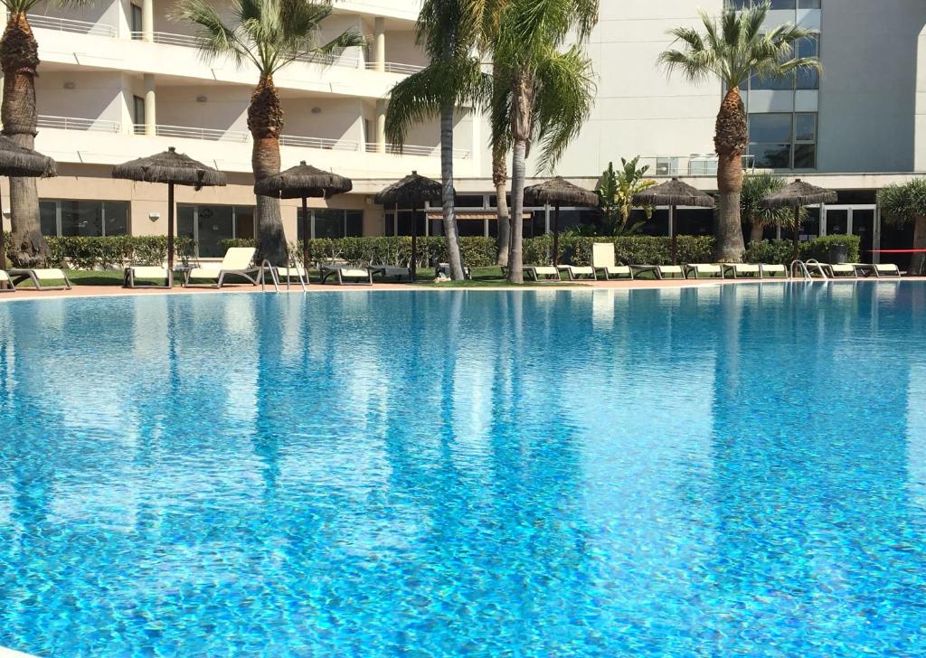 卡耐特蒂贝兰格AGH卡内特酒店的一座棕榈树和遮阳伞的大型游泳池