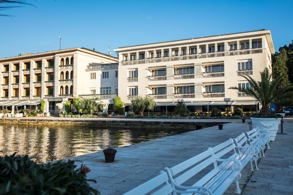 布里俄尼Brijuni Hotel Istra的两座白长椅的河边的建筑物