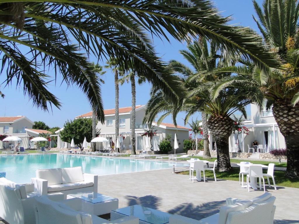 阿依纳帕梦蕾珀酒店的一个带白色椅子和棕榈树的度假游泳池