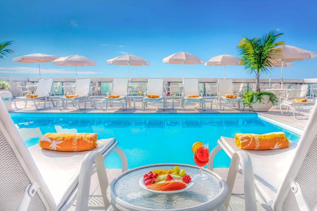 里约热内卢科帕卡巴纳温莎怡东酒店的一个带椅子和水果桌的度假游泳池