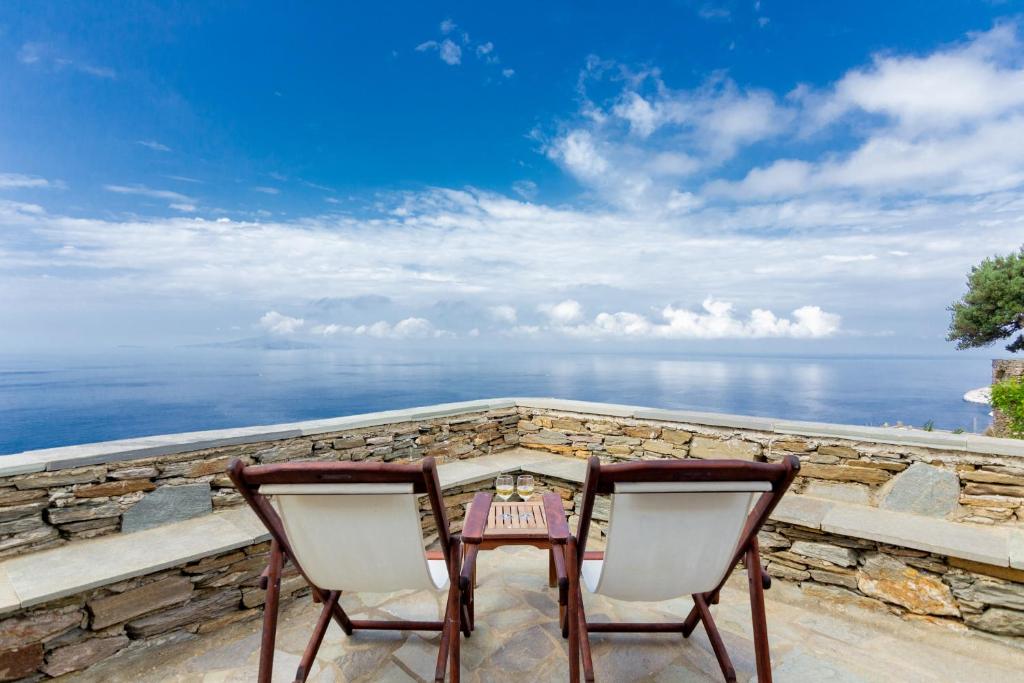EpiskopiónAndros Serenity Adults Only Residences的阳台配有一张桌子和两把椅子,享有海景