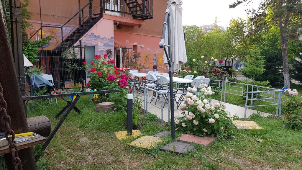 马马亚Hotel-Hostel Mignon Mamaia -private rooms with free parking的一座花园,在一座建筑前,花园内摆放着遮阳伞和鲜花