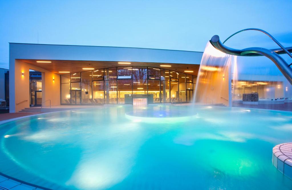 巴特拉德克斯堡德尔帕克斯姆维塔酒店的一座大型游泳池,位于一座建筑中,设有瀑布