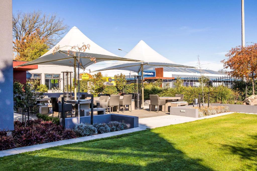 基督城Hotel Elms Christchurch, Ascend Hotel Collection的一个带桌椅和遮阳伞的庭院