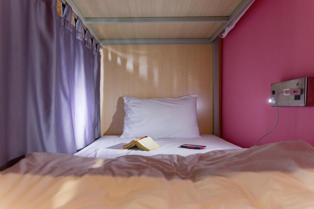曼谷西亚梅子旅馆的一间卧室配有一张床,上面有一本书
