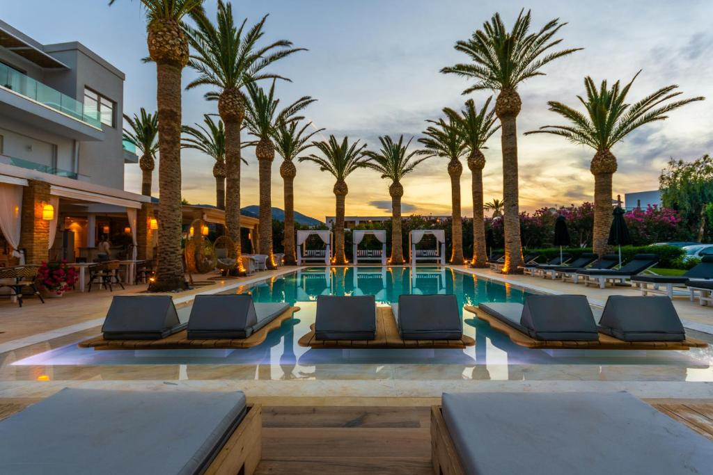 玛利亚Drossia Palms Hotel and Nisos Beach Suites的酒店游泳池拥有棕榈树和躺椅