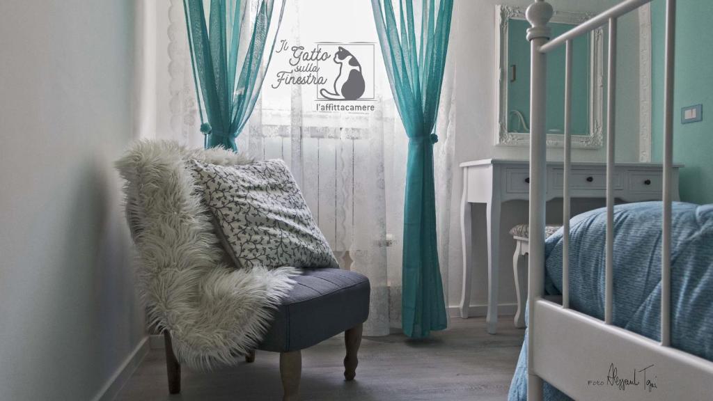 耶西Il Gatto Sulla Finestra的一间卧室配有椅子和一张带绿色窗帘的床