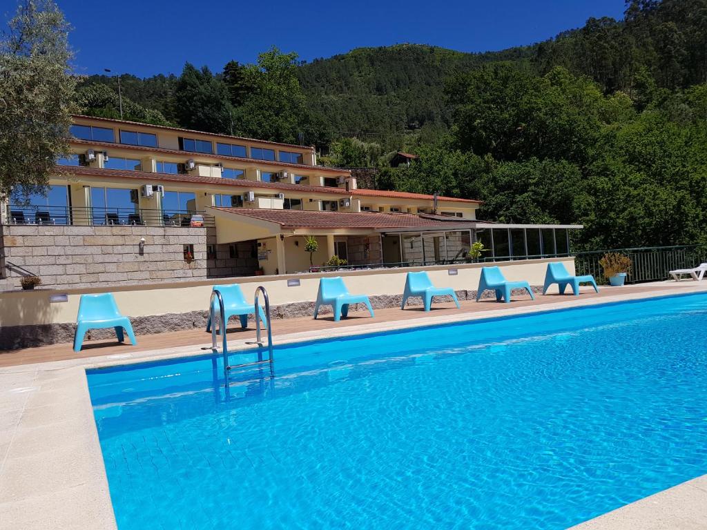 吉尔斯格雷斯拉戈亚阿苏尔酒店的一座带蓝色椅子的游泳池,位于大楼旁