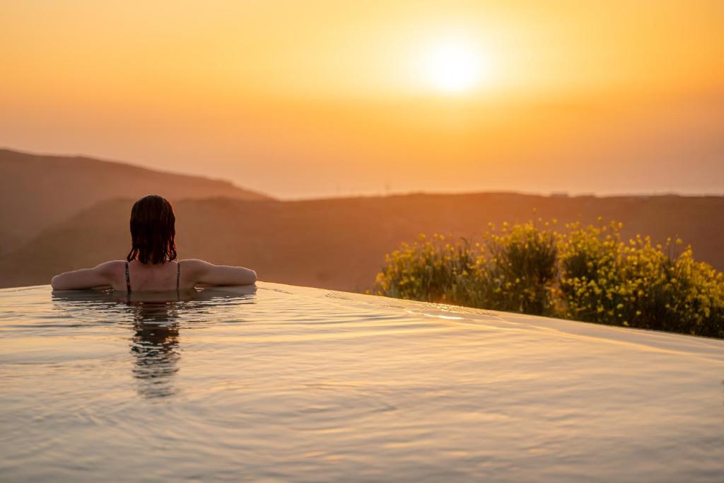 科里夏Agrikea的坐在无边游泳池中观看日落的女人