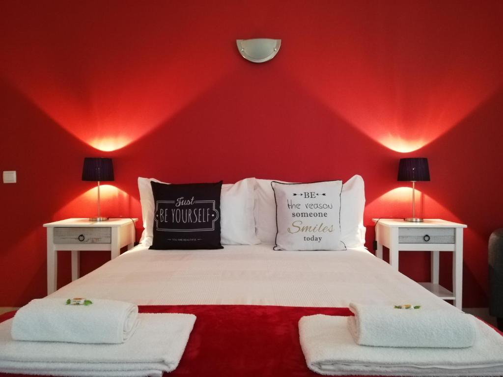 拉戈斯Blue Moon GuestHouse的一间红色墙壁的卧室和一张带两张桌子的床