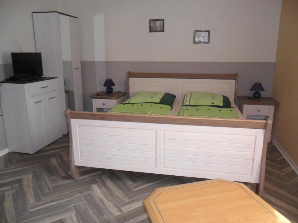 乌曼茨Pension Sabine的一间卧室配有一张带绿色枕头的床和电视。