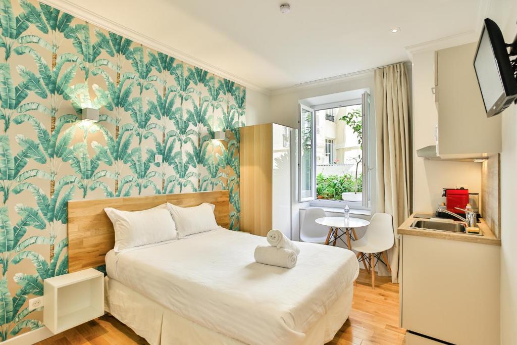 尼斯美丽的家 - 丽都一室公寓的一间卧室配有一张带热带壁纸的大床