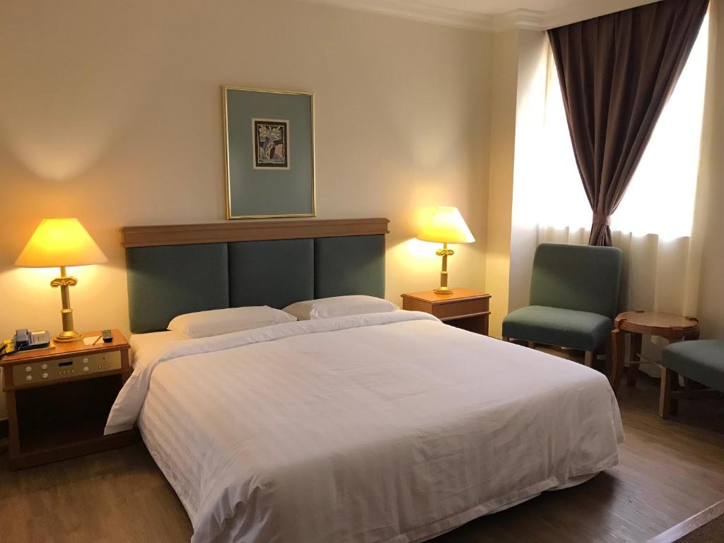 拿笃The Executive Hotel Lahad Datu的卧室配有一张白色大床和一把椅子