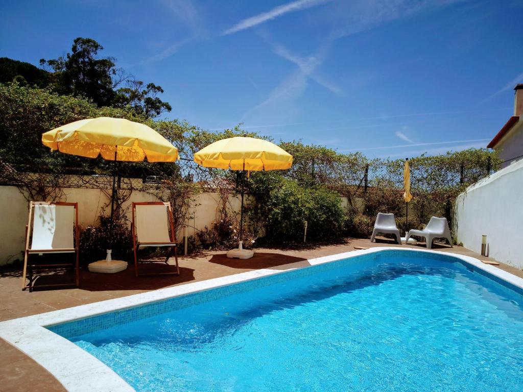 帕尔梅拉Casa de Atalaia的一个带两把遮阳伞和两把椅子的游泳池和一个游泳池