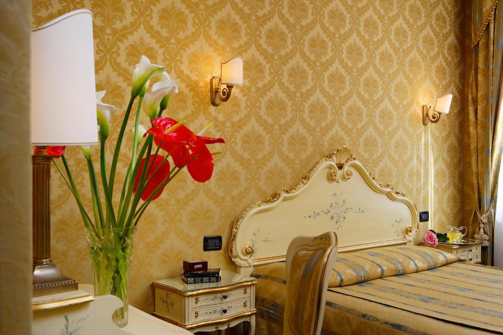 威尼斯高瑞兹酒店的一间卧室配有一张床和一个红色花瓶