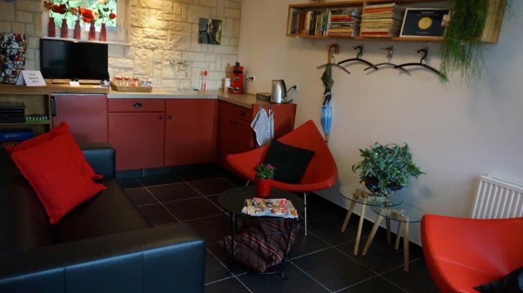 艾斯登Huize Mesch的一间带红色椅子的客厅和一间厨房