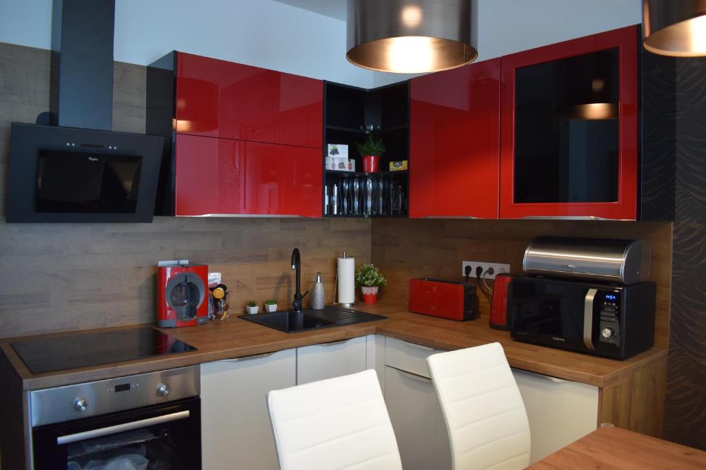 巴拉通雷勒Lido Riviéra, Relux Apartman Balatonlelle的厨房配有红色橱柜、水槽和微波炉