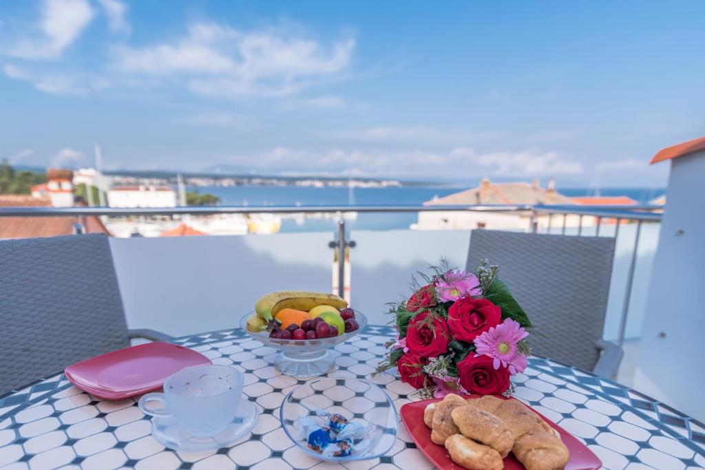 马林斯卡Apartments Vila DK的阳台上摆放着一盘食物和鲜花的桌子