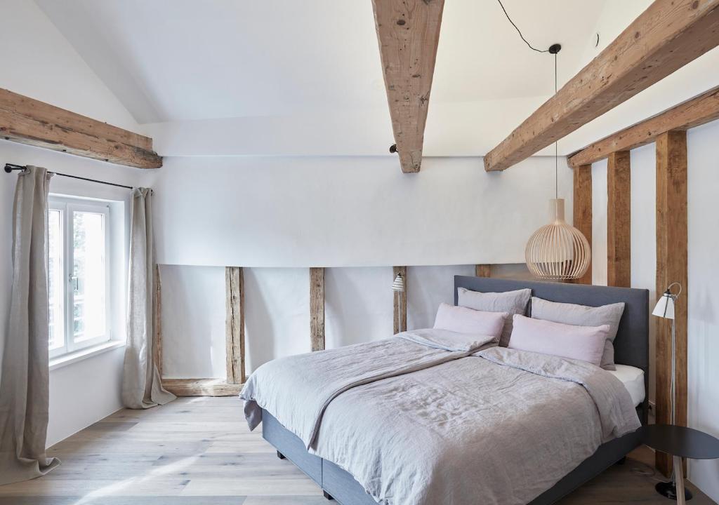 因斯布鲁克Faktorei的一间卧室设有一张大床,拥有白色的墙壁和木梁