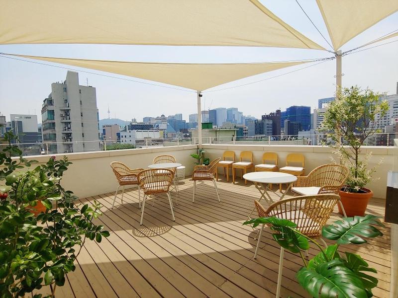 首尔Tong Tong Petit Hotel的阳台配有桌椅和雨伞。