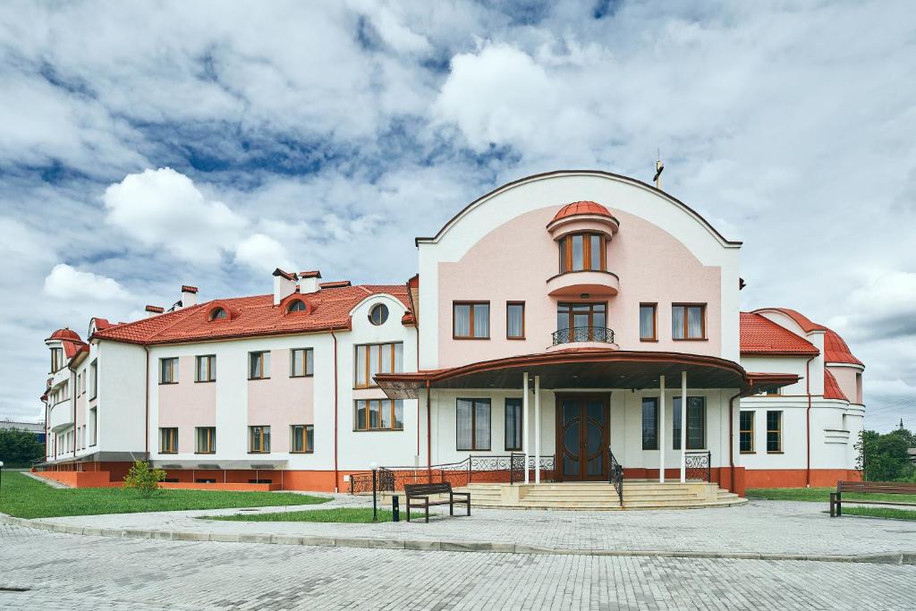 利沃夫Hotel Patriarshyi的一座白色的大建筑,有红色的屋顶