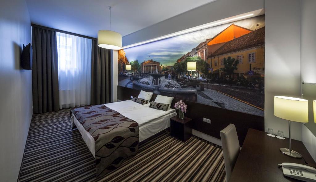 维尔纽斯维尔纽斯城市酒店的卧室配有一张床,墙上挂有绘画作品