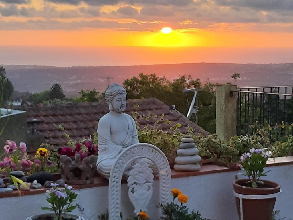 辛特拉Isa's Home的雕像坐在墙上,背面有日落
