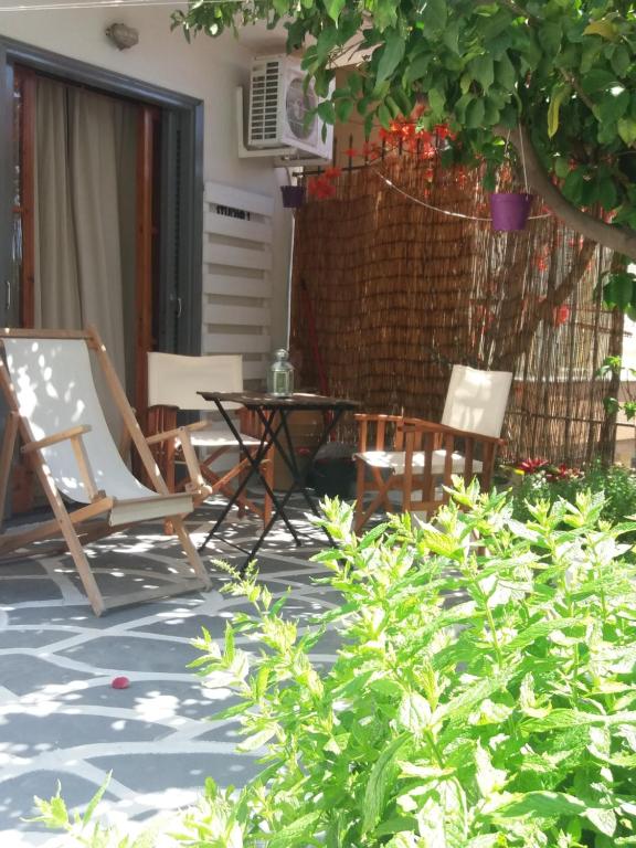 波罗斯poros apartment in garden的一个带椅子和桌子的庭院和一棵树