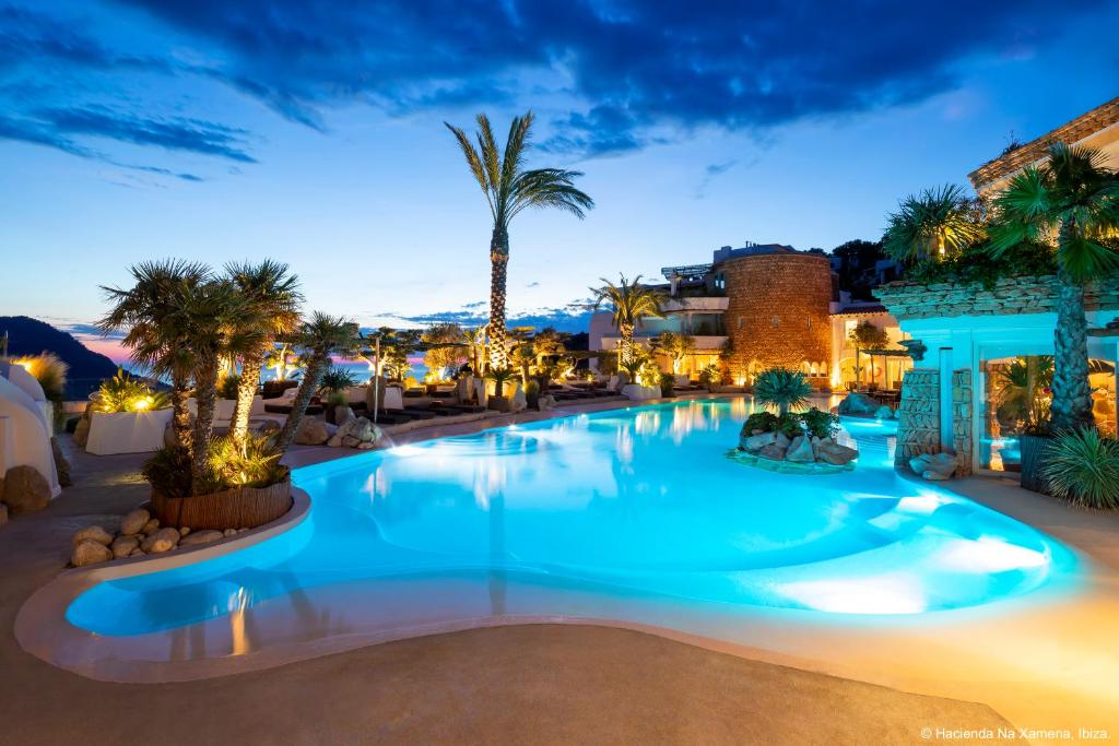 纳格泽梅纳伊维萨泽梅纳牧场酒店的棕榈树和建筑的夜间游泳池