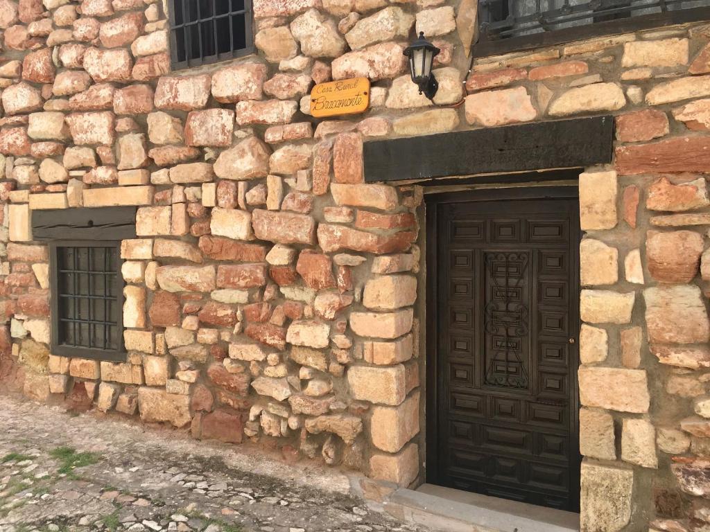 阿尔卡拉斯Casa Rural Bracamonte的一座石头建筑,设有木门和两扇窗户