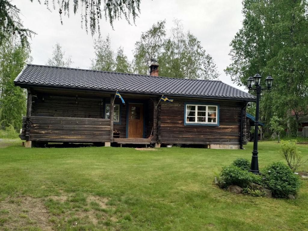 格兰耶德Mysig timmerstuga vid sjön Björken的绿色草坪庭院中的小木屋