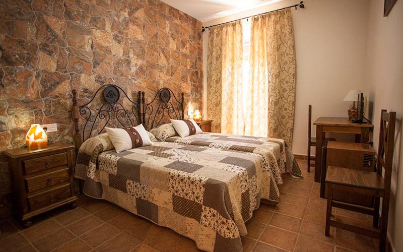 阿拉色那卡萨农村辛科巴尔肯斯旅馆的一间卧室设有一张大床和石墙