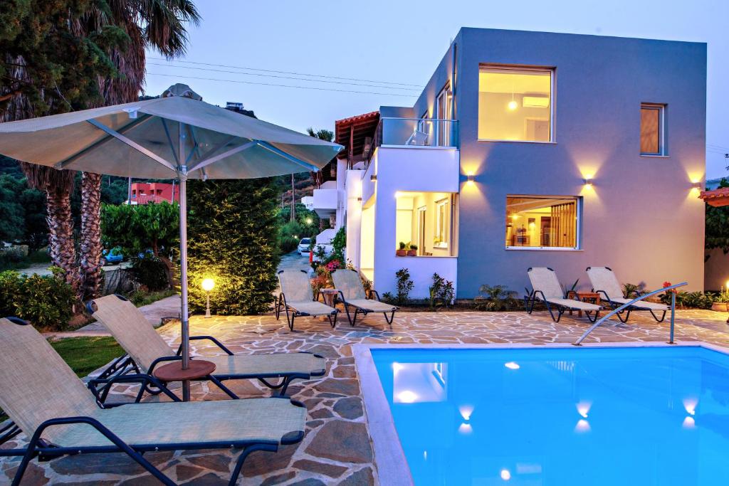 普拉基亚斯IRIDA Guesthouse by the Pool的房屋旁的游泳池配有椅子和遮阳伞