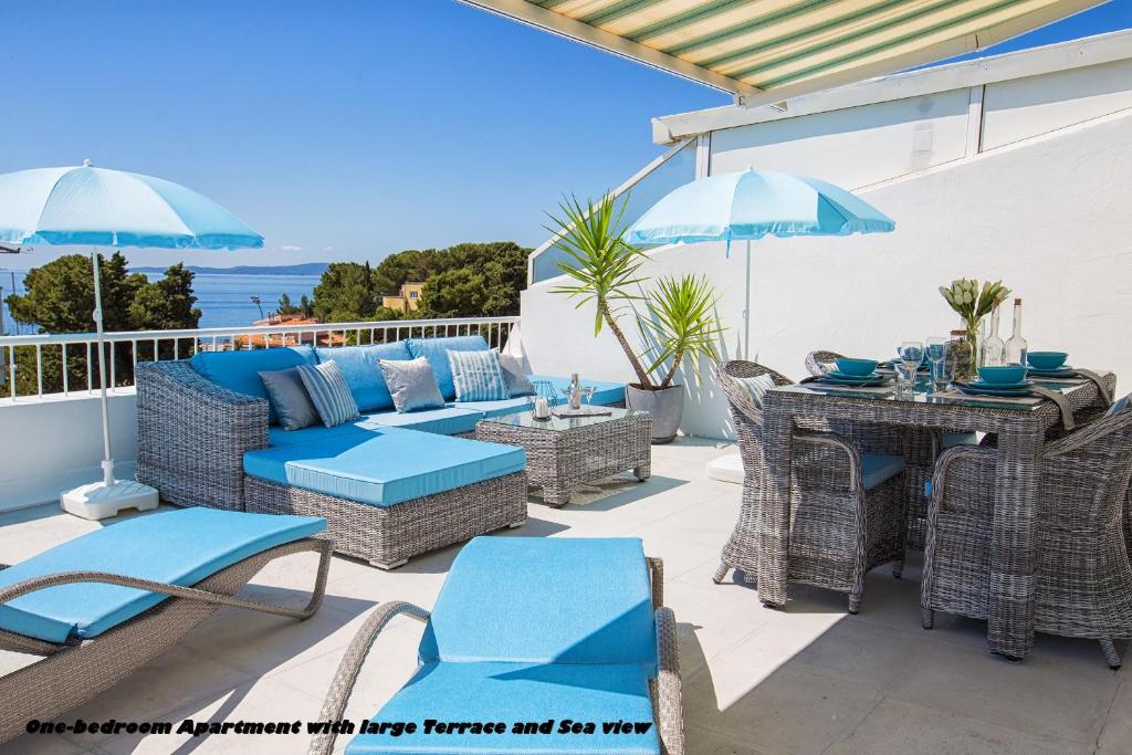 斯普利特Holiday Apartments Split的一个带蓝色椅子、桌子和遮阳伞的庭院