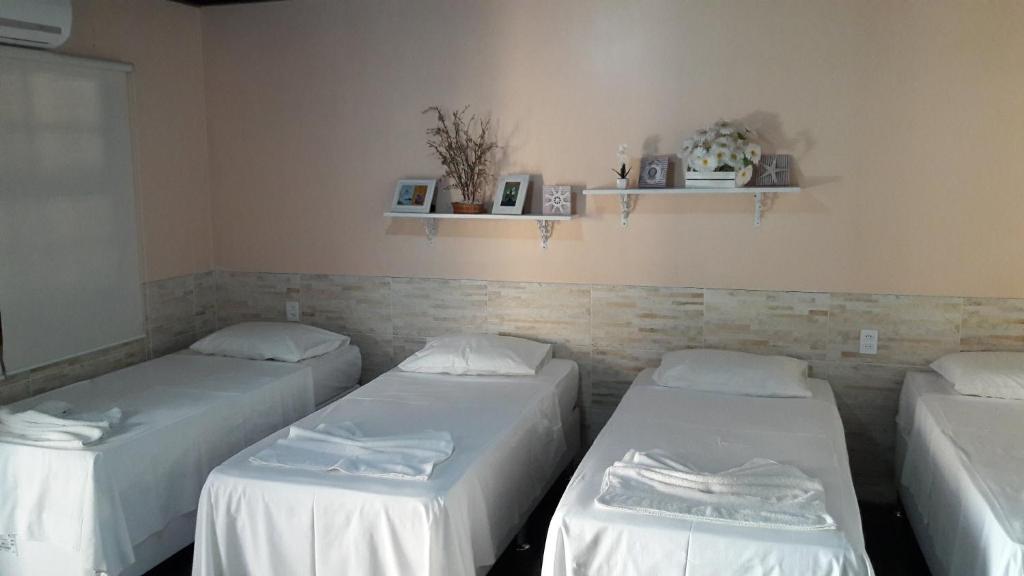 阿拉亚尔-杜卡布Casa das Orquideas的配有白色床单的客房内的三张床