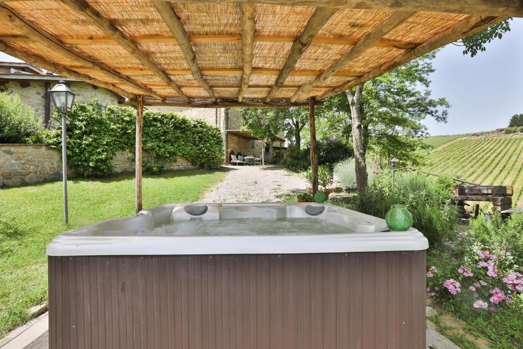 因普鲁内塔Il Vichiaccio Country House的庭院内的热水浴池,配有木制凉棚