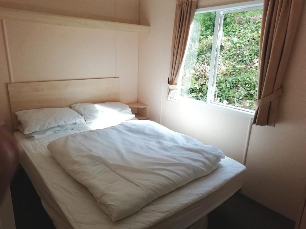 斯沃尼奇Swanage bay caravan的窗户客房内的一张白色床