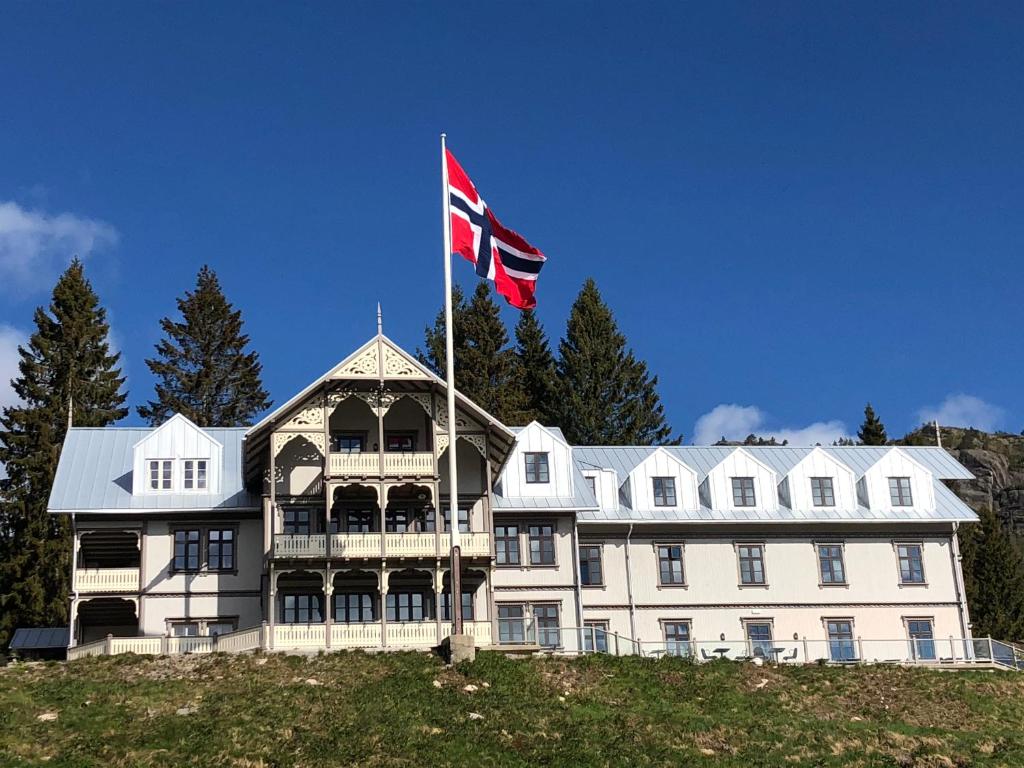 ÅseralHotell Eikerapen Gjestegård Åseral的一座白色的大房子,上面有吊旗