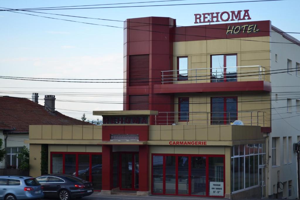 皮特什蒂Hotel Rehoma的一座红色和黄色的建筑,前面有汽车停放