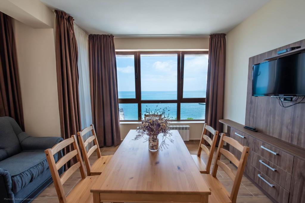 巴尔奇克Balchik Sea View Apartments in Princess Residence的客厅配有木桌、椅子和电视