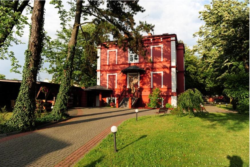 帕比亚尼采印象别墅酒店及餐厅的一座大型红砖建筑,前面有树木