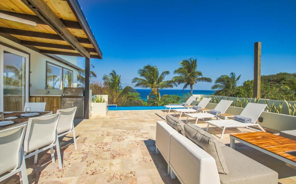 西湾Villa Topaz Above West Bay with 360 Degree Views! 4 Bedroom Option的一个带桌椅的户外庭院和大海