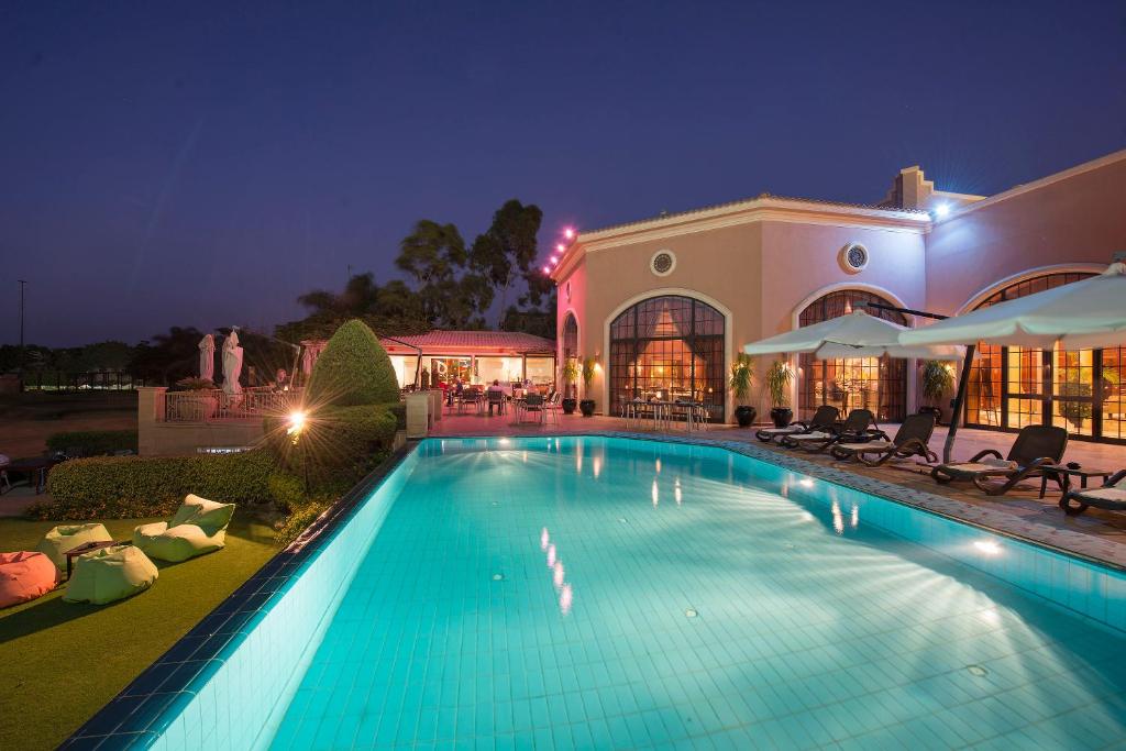 艾因苏赫纳Stella Di Mare Golf Hotel的一座游泳池,在晚上在建筑物前