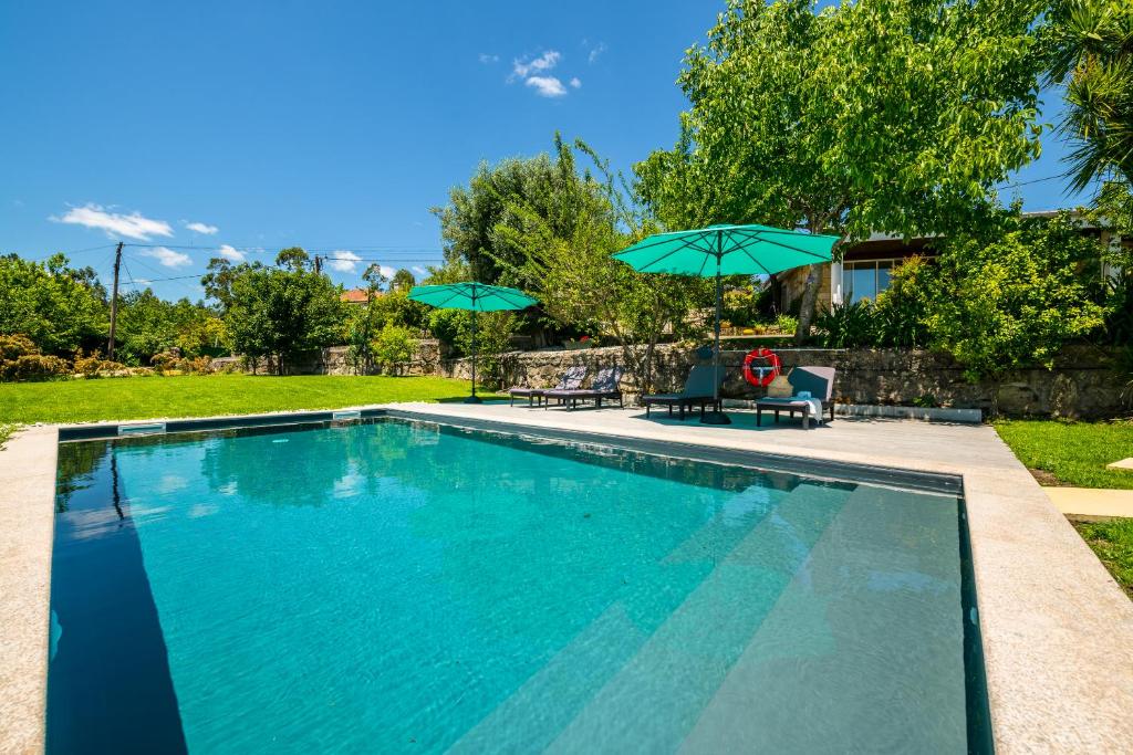 Areias de VilarCasa de Campo - Olive House的一个带两把遮阳伞和两把椅子的游泳池