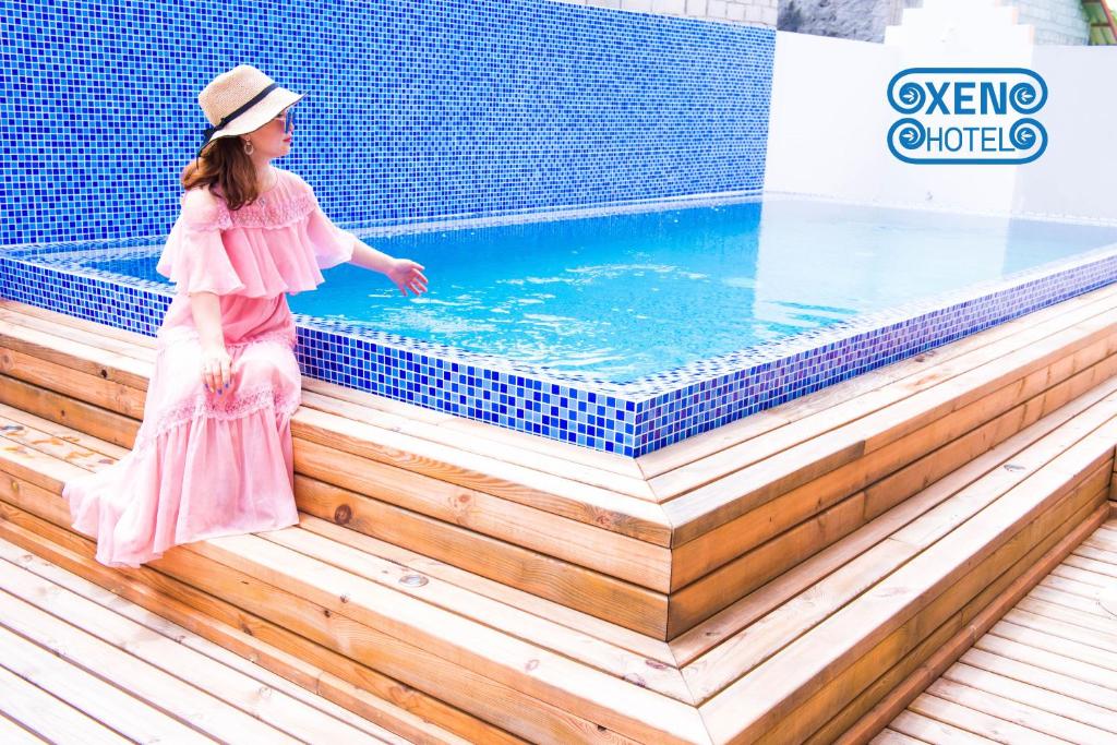 MiduXen Midu Hotel Addu City Maldives的身着粉红色连衣裙的小女孩站在游泳池旁边