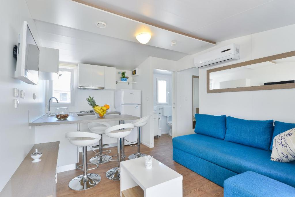 图兰杰Mobile house Nord 1 Laguna的一间带蓝色沙发的客厅和一间厨房