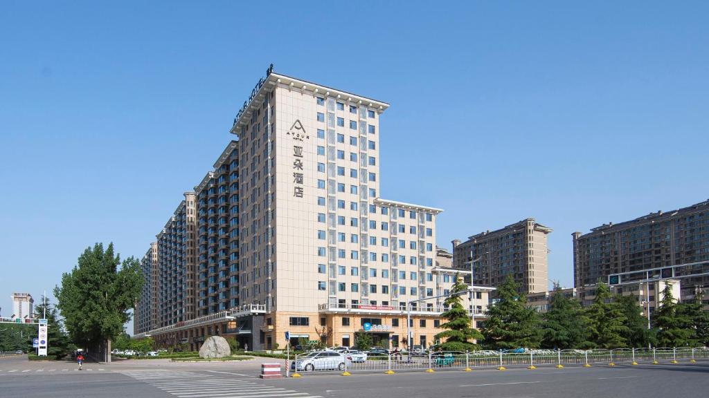 侯马侯马新田广场亚朵酒店的城市中一座高大的白色建筑,设有停车场
