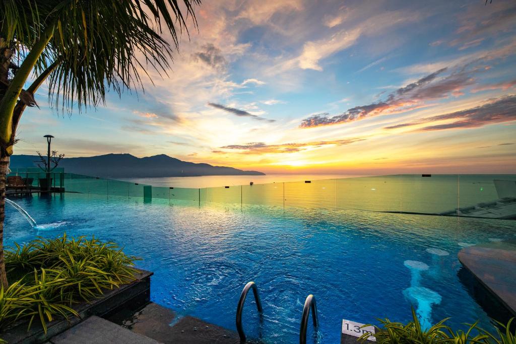 岘港Sala Danang Beach Hotel的日落时分享有海洋美景的游泳池