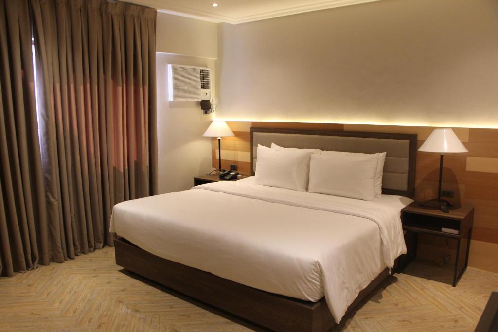 巴科洛德Acacia Hotel Bacolod的卧室配有一张带白色床单和枕头的大床。